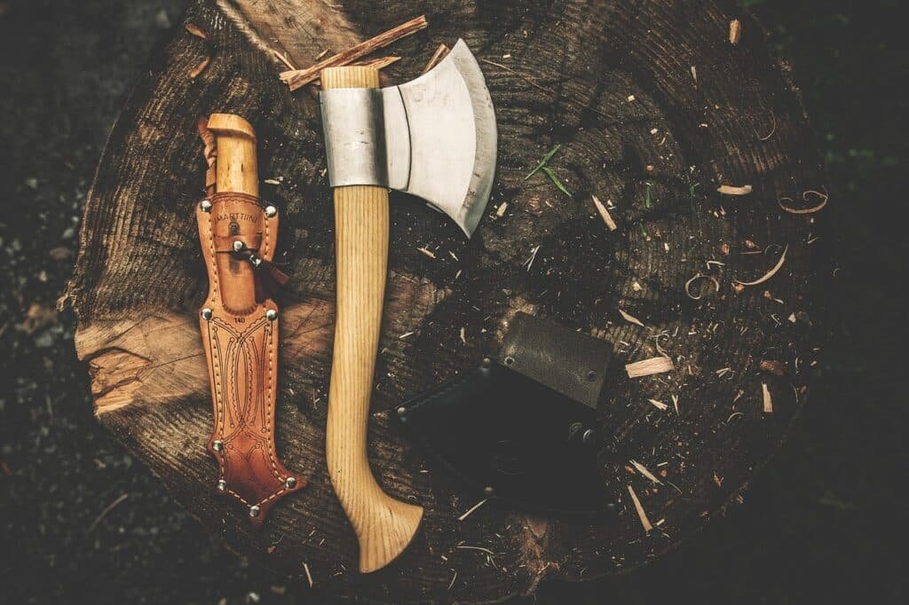 Vintage-themed image showcasing essential 'Axe Throwing Fundamentals': An old-world axe and knife resting gracefully on a rustic wooden surface amidst a lush natural backdrop