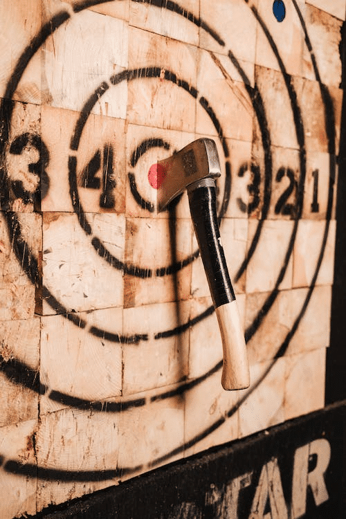 An exhilarating axe throwing game in action, showcasing a precise throw as the axe lands perfectly in the center of the wooden target.