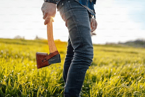 Man demonstrating axe throwing safety with a confident grip on the axe, promoting responsible and controlled technique