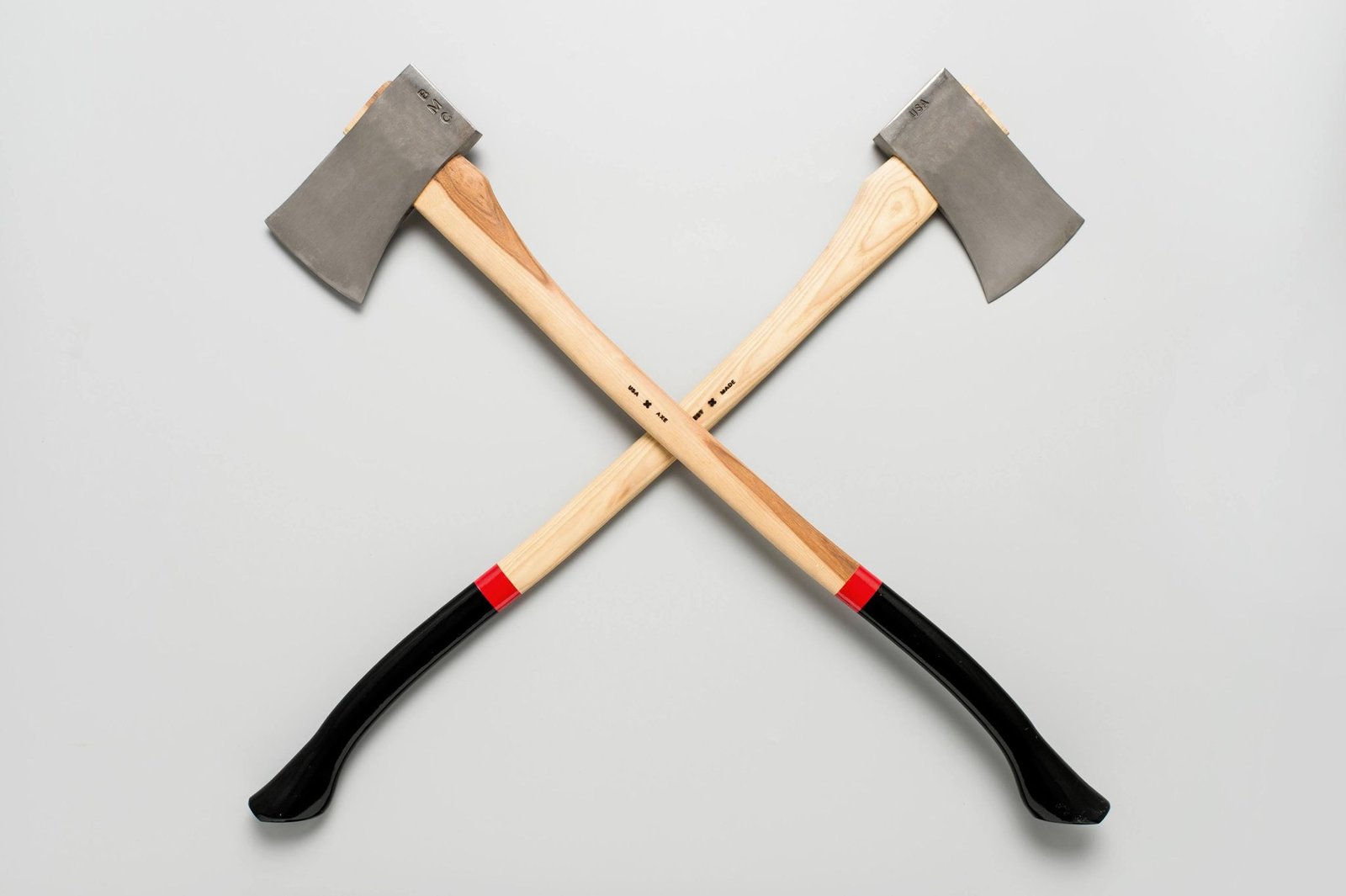 Two axes, intersecting on a neutral gray background, representing the exciting and invigorating activity of axe throwing. Discover the benefits of axe throwing, a thrilling recreational pursuit that fosters focus, precision, and stress relief.